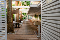 Ingresso alla veranda dell'Hotel Saraceno con pavimento in legno, alberi, amache e tavoli all'aperto.
