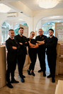 Cinque membri dello staff dell'Hotel Saraceno in divisa nera posano a braccia conserte all'interno della sala ristorante.
