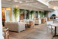 Veranda esterna dell'Hotel Saraceno con pavimentazione in legno, divani in vimini, poltrone in legno e coperture bianche.